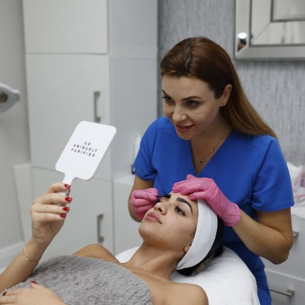 A client checking the final result in a handheld mirror after a beauty enhancement session.
