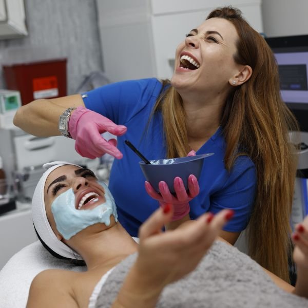A smiling client sharing a lighthearted moment with her beauty professional during a facial treatment.