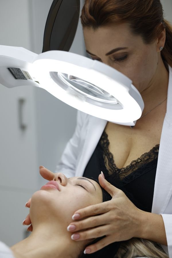 A certified skincare expert inspecting a client’s skin using magnification for accurate diagnosis.