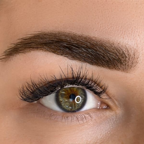 Close-up of a perfectly shaped eyebrow and curled lashes after enhancement treatment.
