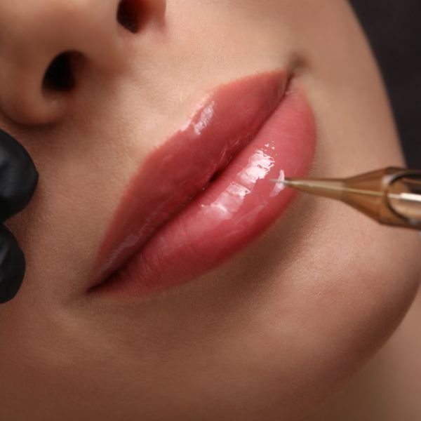A close-up of a permanent makeup specialist performing a lip tattoo treatment.