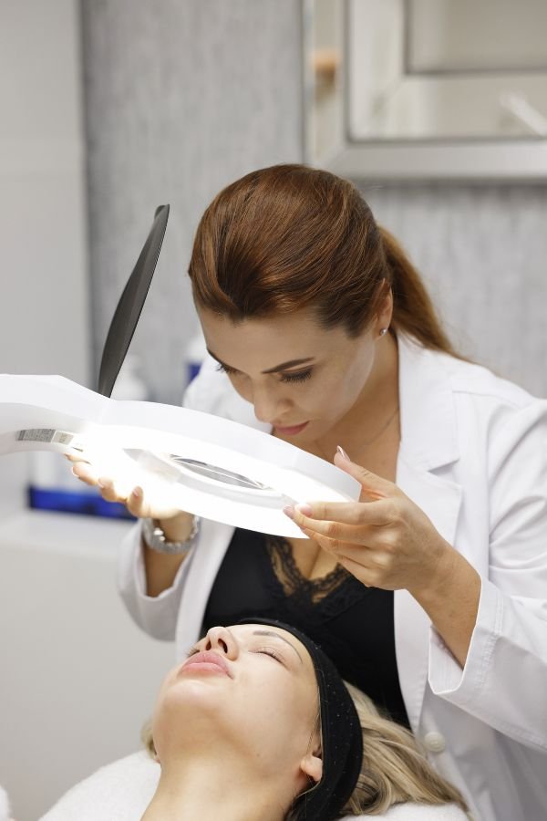 Irina using a magnifying lamp to examine client's skin